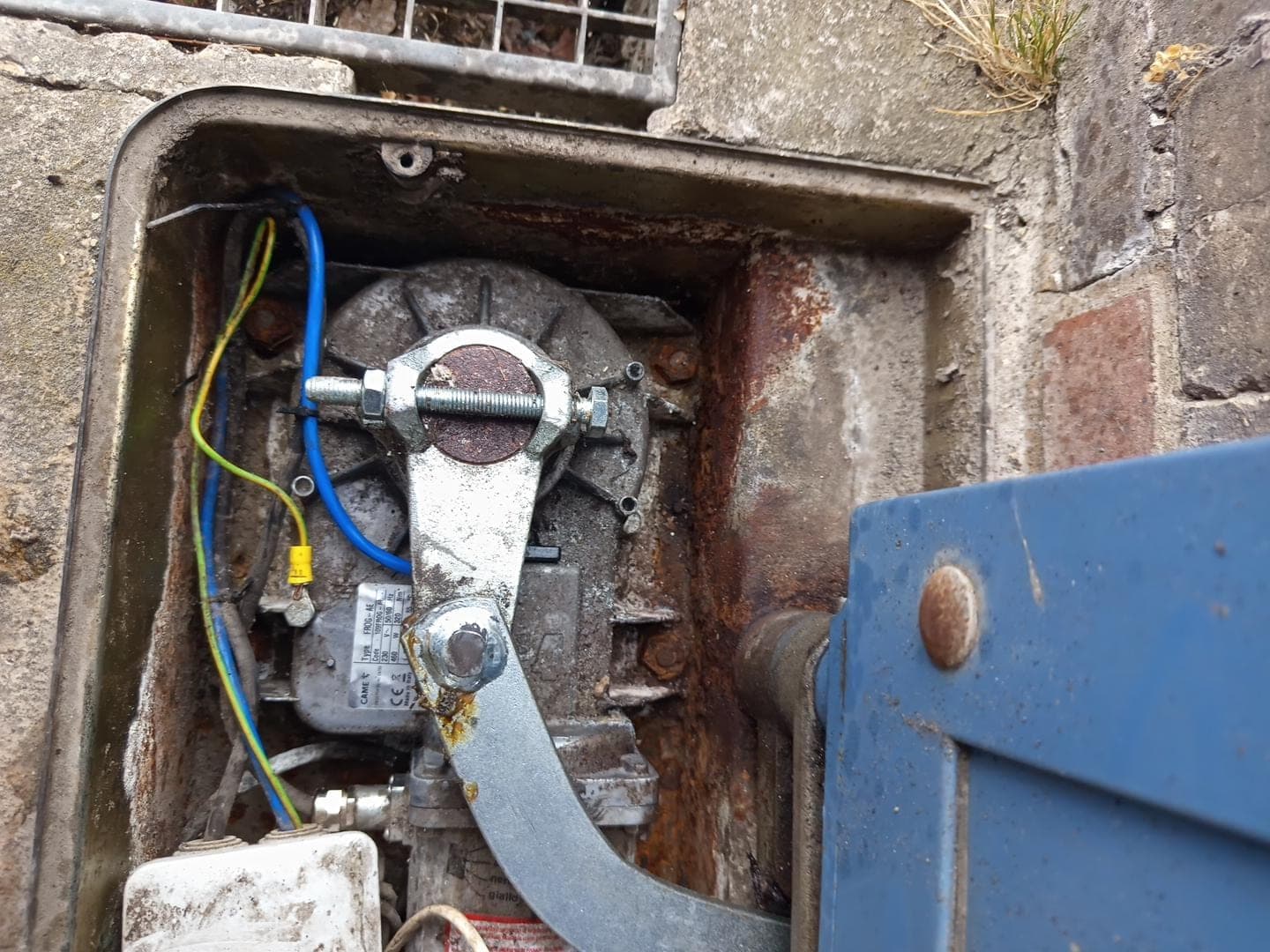Moteur enterré CAME FROG-AE et son bras de liaison dans le caisson de fondation d'un portail battant à Ézy-sur-Eure, Eure