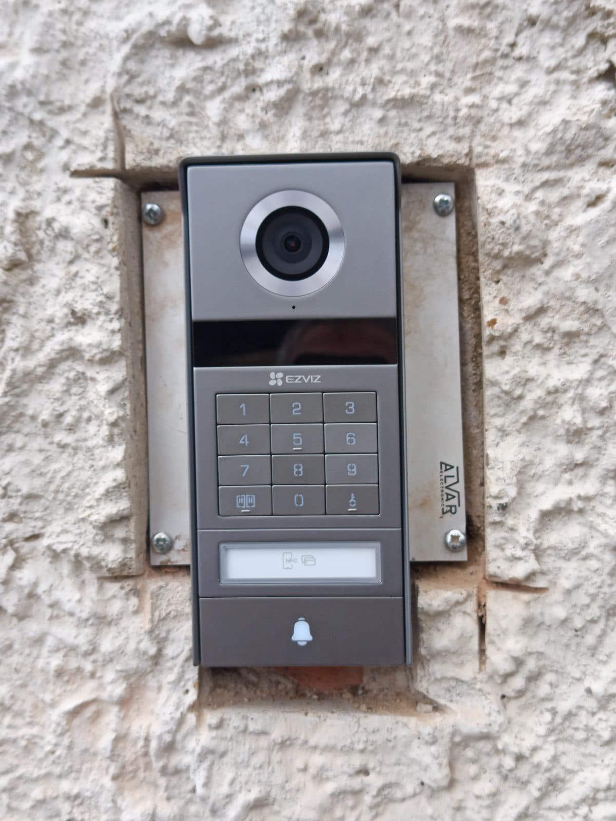Platine de rue EZVIZ TP9 Pro avec caméra 4K, clavier à code et lecteur NFC, installée sur un mur en pierre à La Queue-les-Yvelines