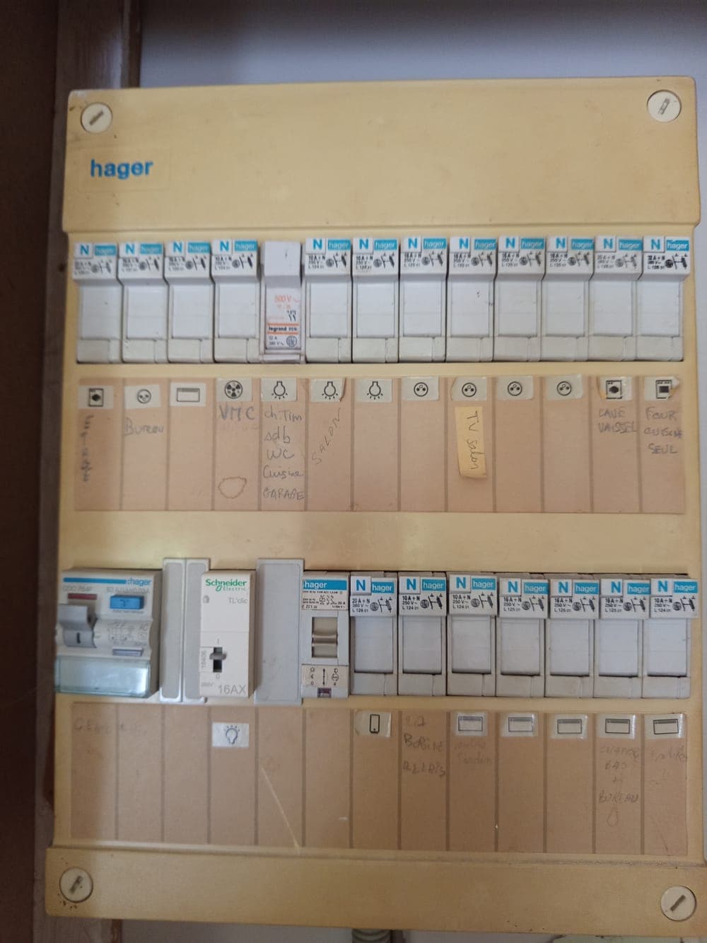 Ancien tableau électrique Hager jauni avec son télérupteur et ses étiquettes manuscrites, avant remplacement à Thoiry
