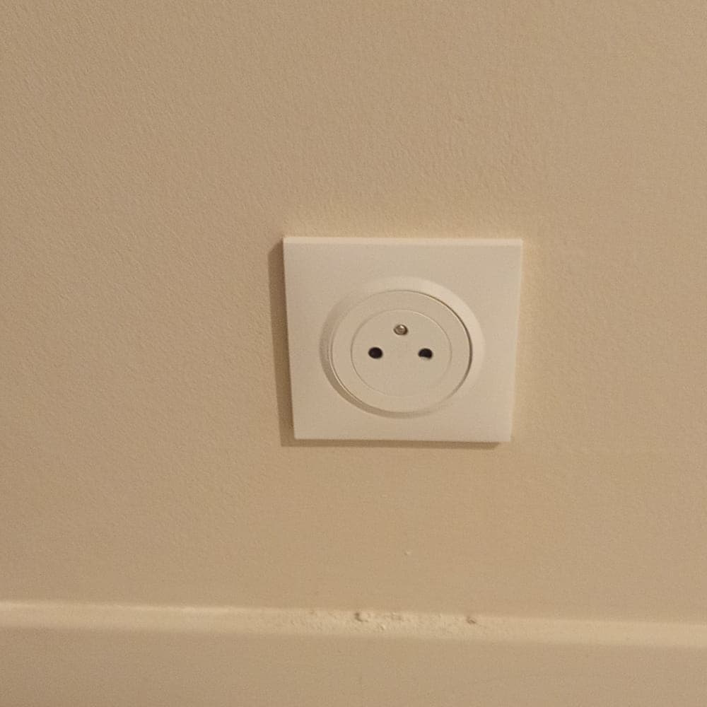 Prise de courant Legrand Dooxie neuve avec broche de terre visible, installée à l'étage d'une maison à Thoiry